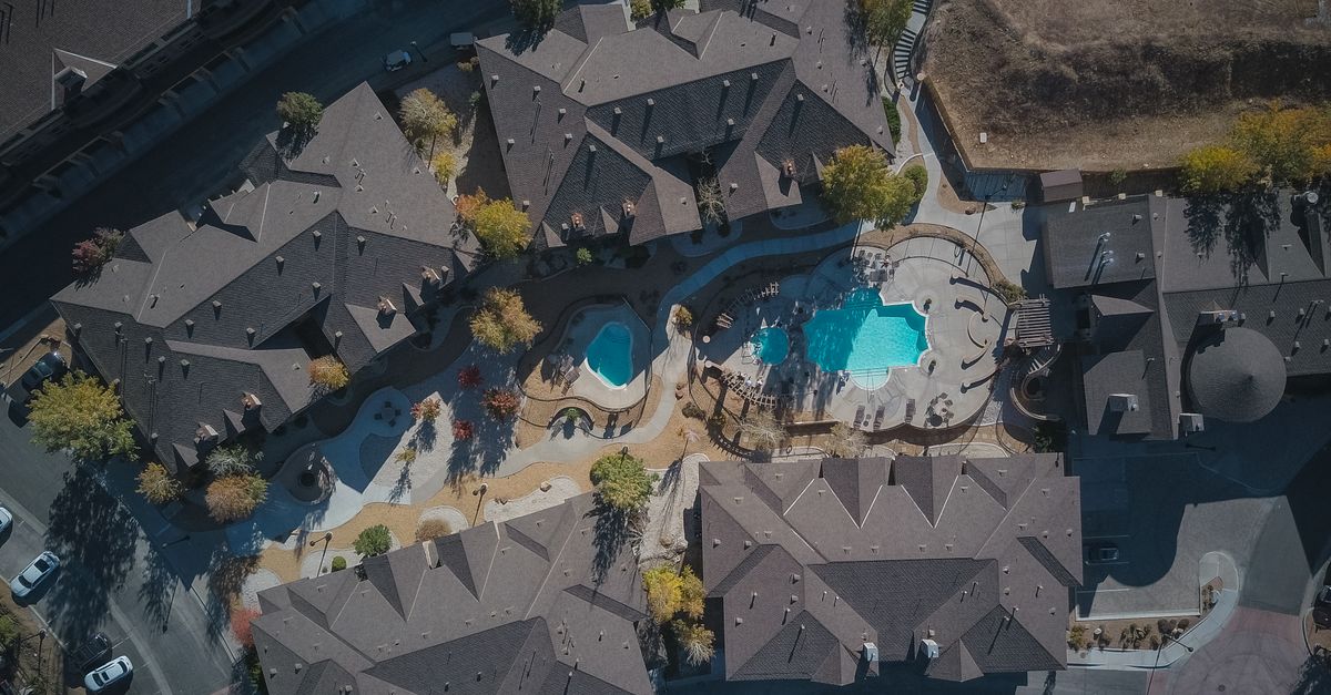 Aerial view of a residential complex with swimming pools and surrounding town architecture.