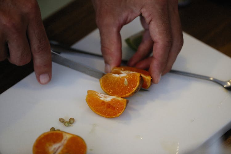 Closeup Of Mans Hands Slicing Satsuma