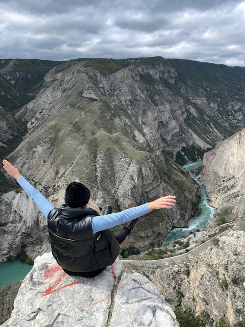 A Person Sitting on the Edge of a Cliff