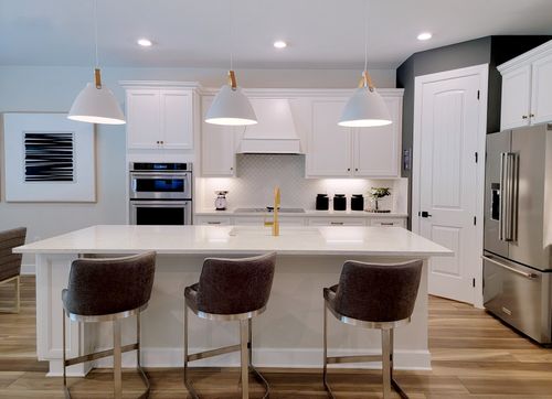 Free Sleek and modern kitchen with minimalist design featuring white cabinetry and elegant lighting. Stock Photo