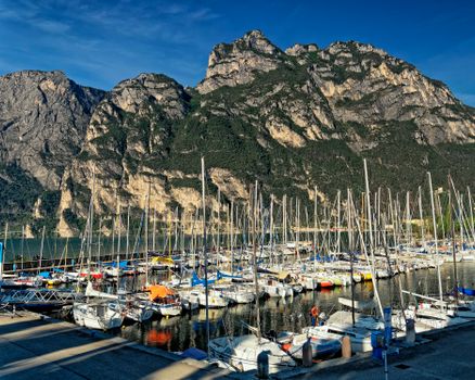 Captivating view of a marina filled with sailboats, set against Italy's stunning mountains.