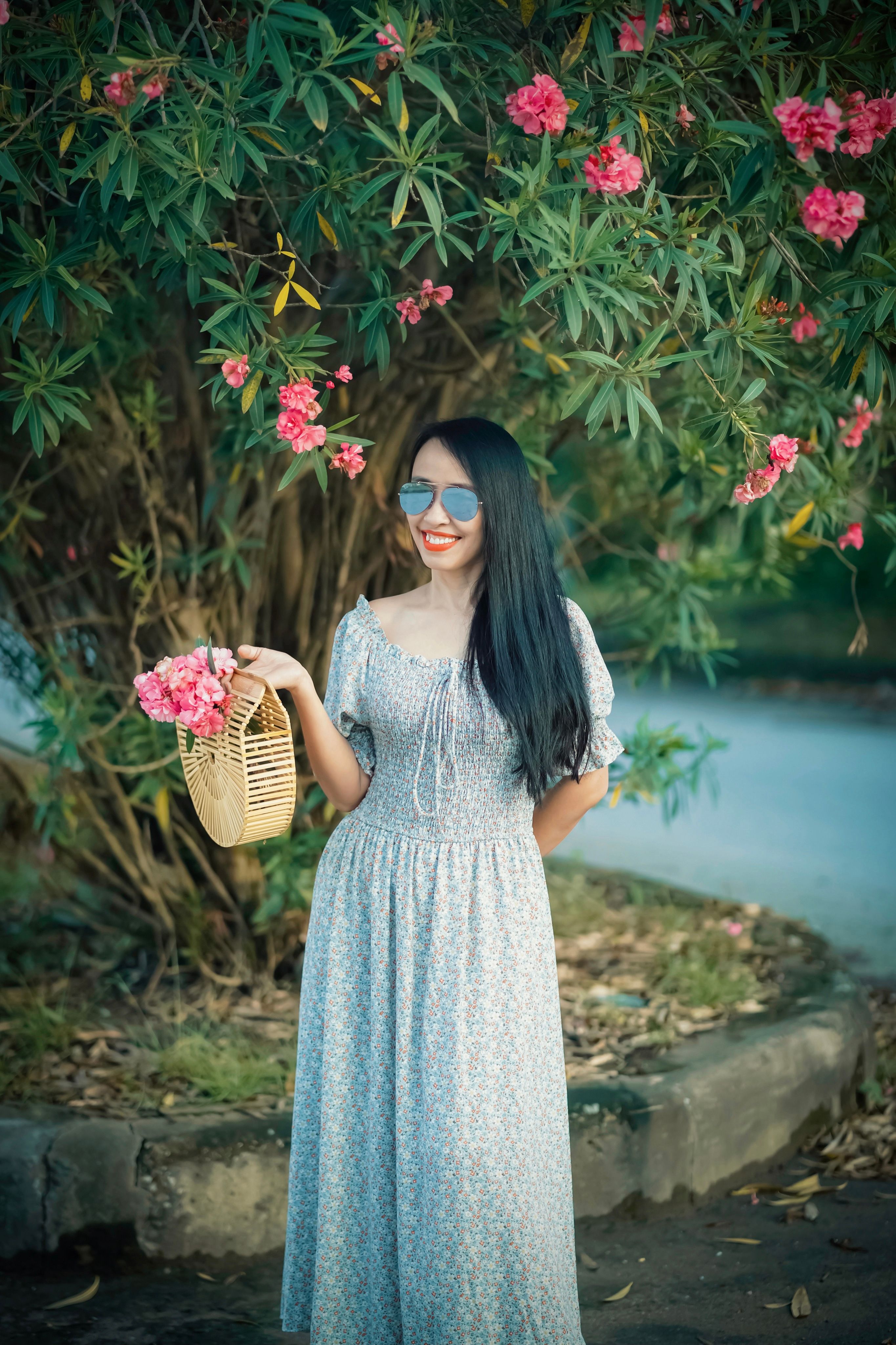 Woman in Floral Dress Holding a Basket With Pink Flowers · Free Stock Photo