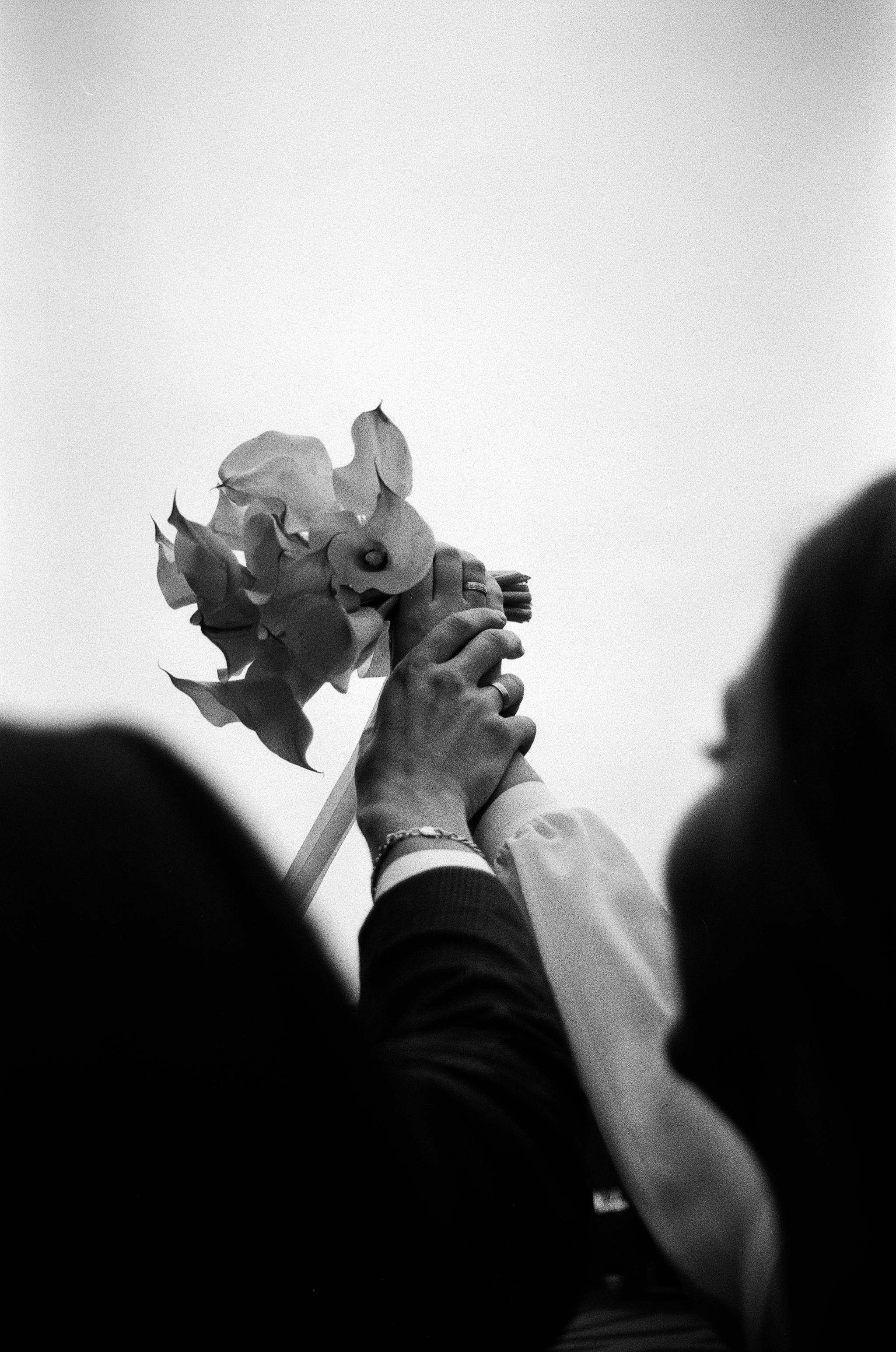 Artistic black and white photo of hands holding a wedding bouquet.