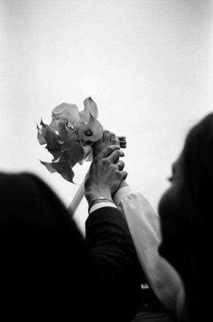 Artistic black and white photo of hands holding a wedding bouquet.