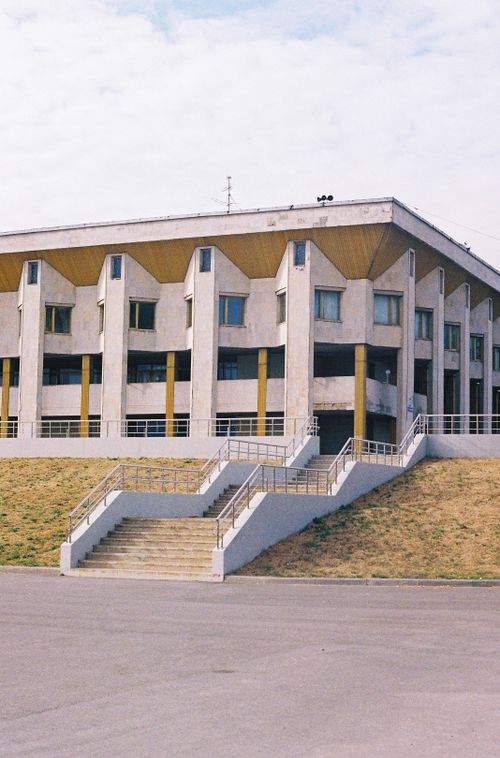Free A modern concrete building with symmetrical windows and cascading steps, set against a partly cloudy sky. Stock Photo