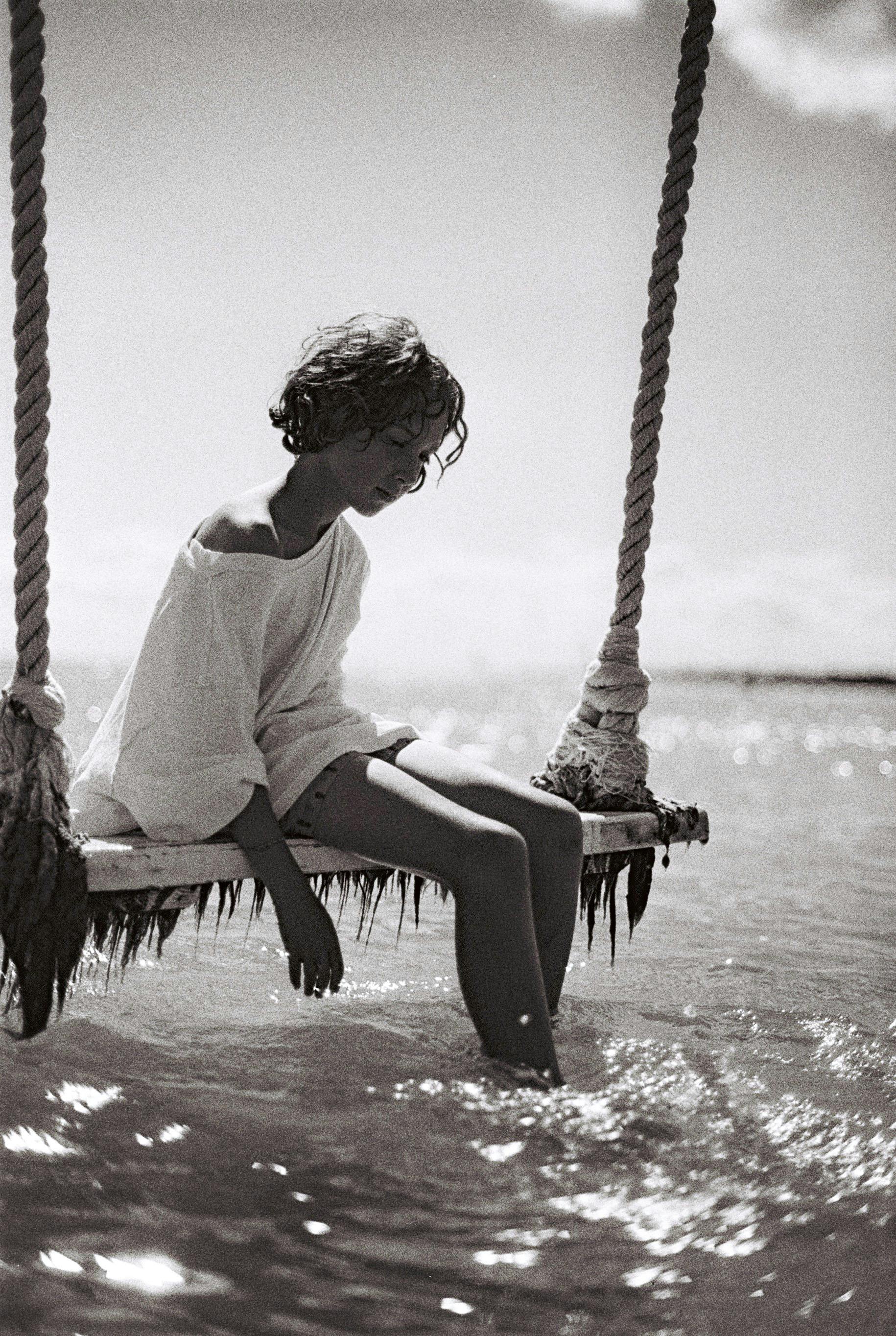 Calm scene of woman on a swing over the ocean in black and white.