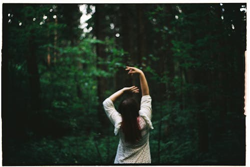 Back View of a Woman with Arms Raised in a Forest 