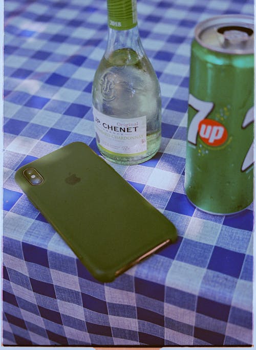 Green iPhone  Near a Soda in Can and a Bottle of Drink