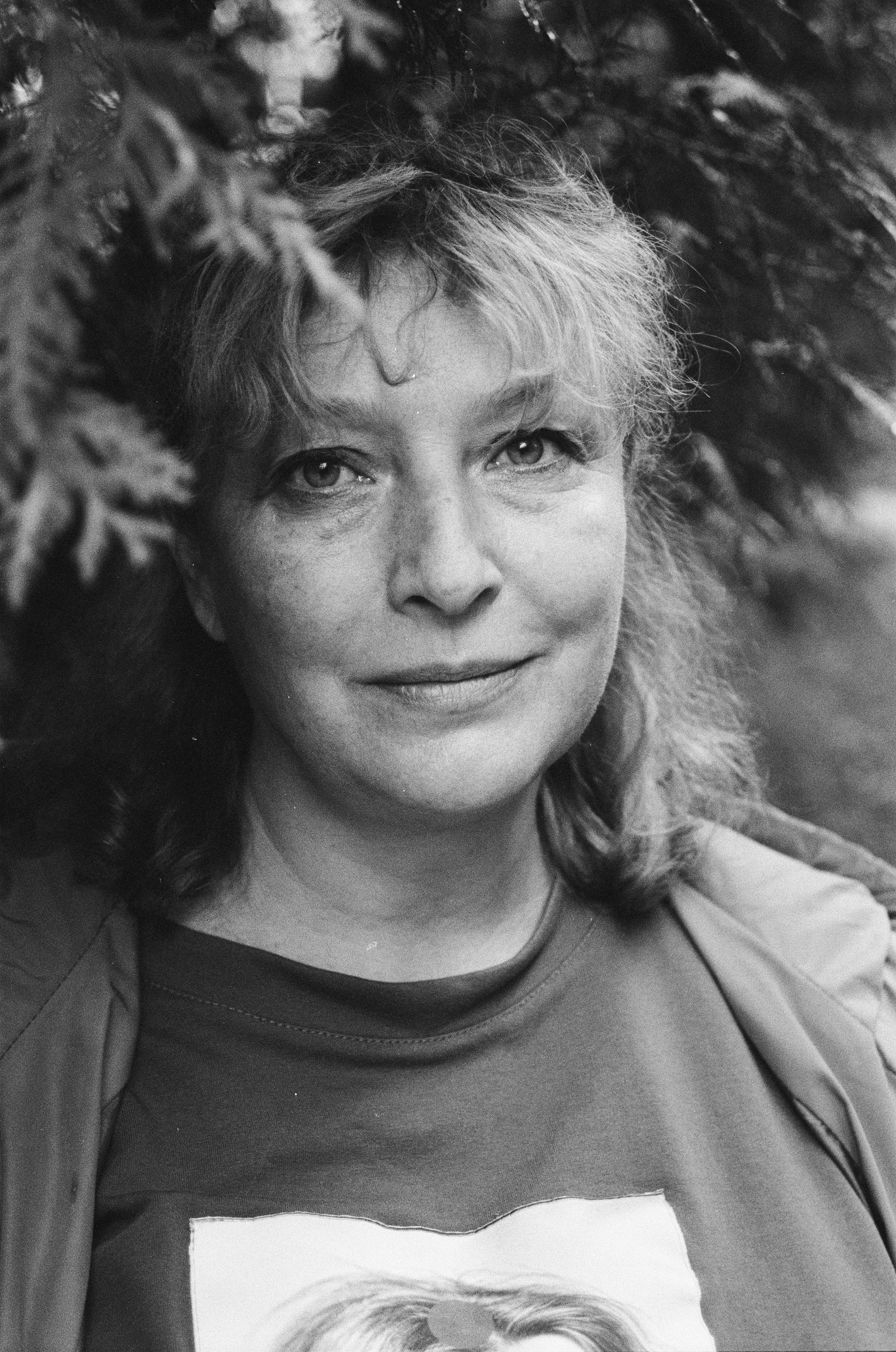 A calming black and white portrait of a smiling woman surrounded by nature.