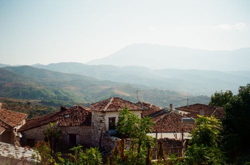 Free Tranquil rural scene featuring rustic houses with tiled roofs against mountainous backdrop. Stock Photo