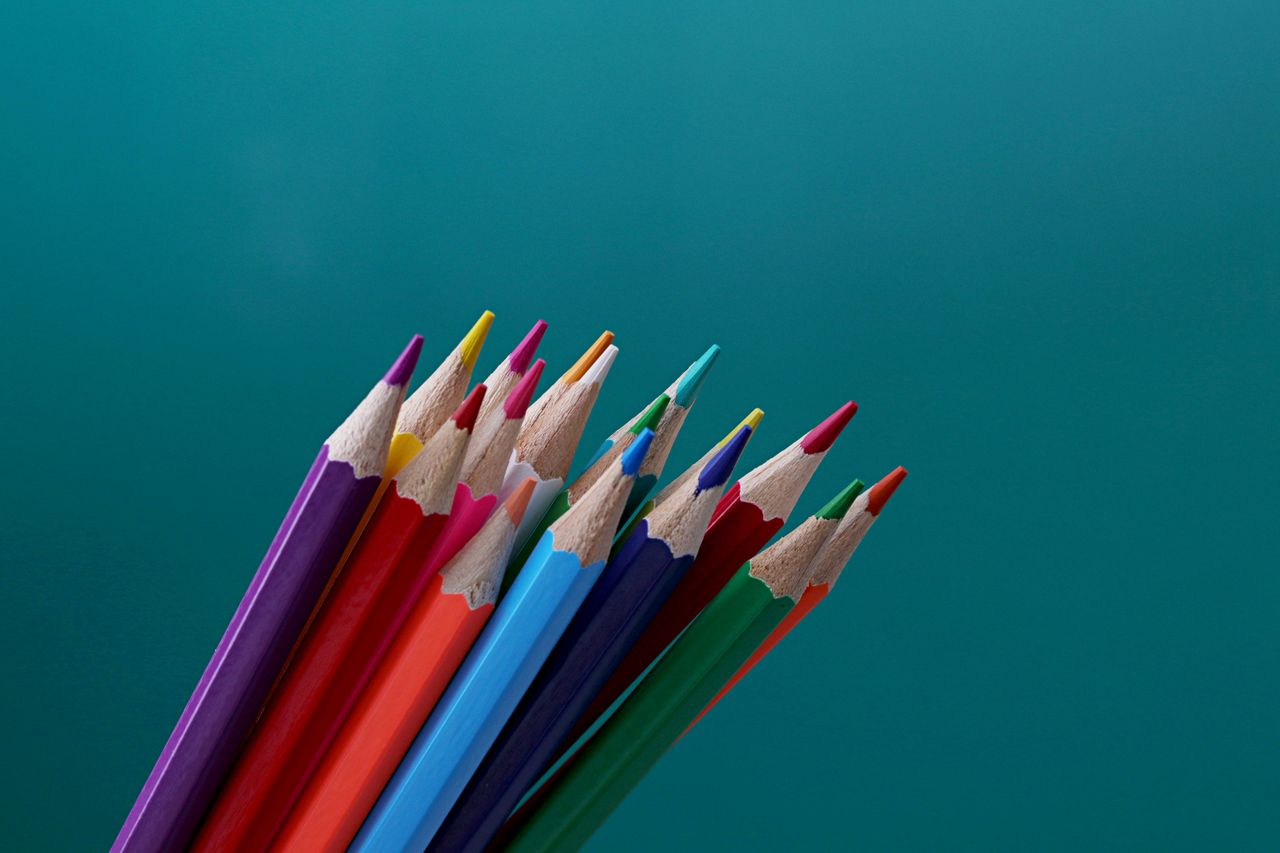 close up of colorful sharpened pencils on teal background perfect for
