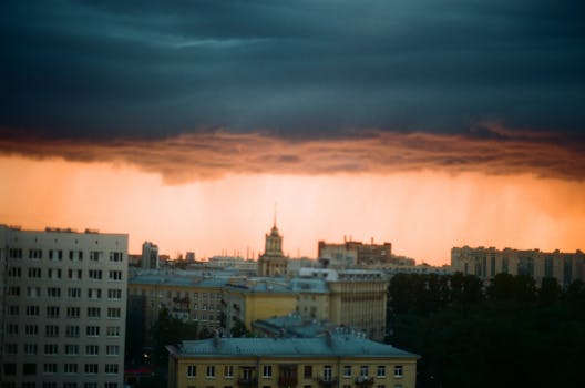 Cityscape under a dramatic sky with approaching storm, creating a dramatic sunset scene.