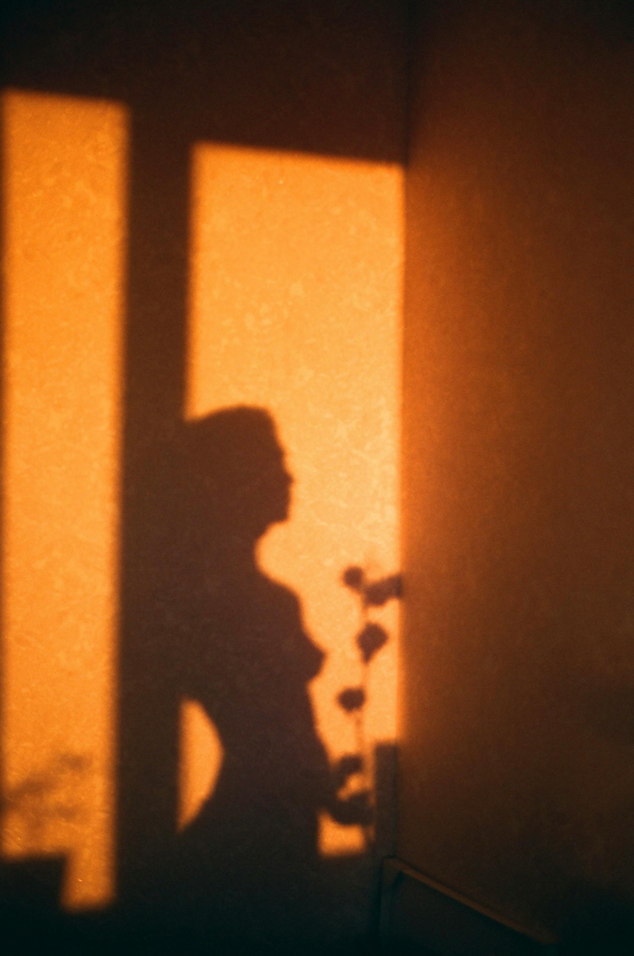 Artistic shadow of a woman on a wall in warm sunlight, creating a peaceful atmosphere.