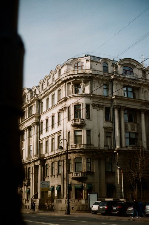 Free Elegant historic building with classic architecture and balconies under a clear sky. Cars parked on street. Stock Photo