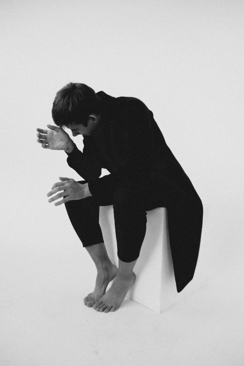 Free Black and white artistic portrait of a man sitting barefoot, conveying emotion. Stock Photo
