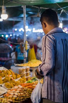 Captivating view of a vendor selling vibrant street food in Cambodia's bustling night market.