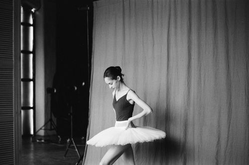 Free Black and white photo of a ballerina adjusting tutu in a studio. Stock Photo
