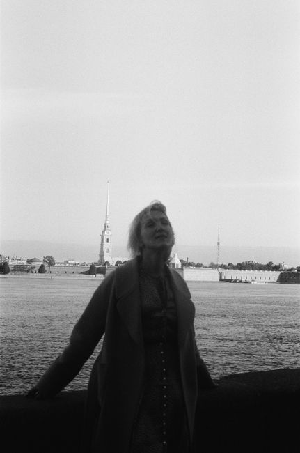 Elegant black and white portrait of a woman on the Saint Petersburg waterfront with iconic cityscape in the background.