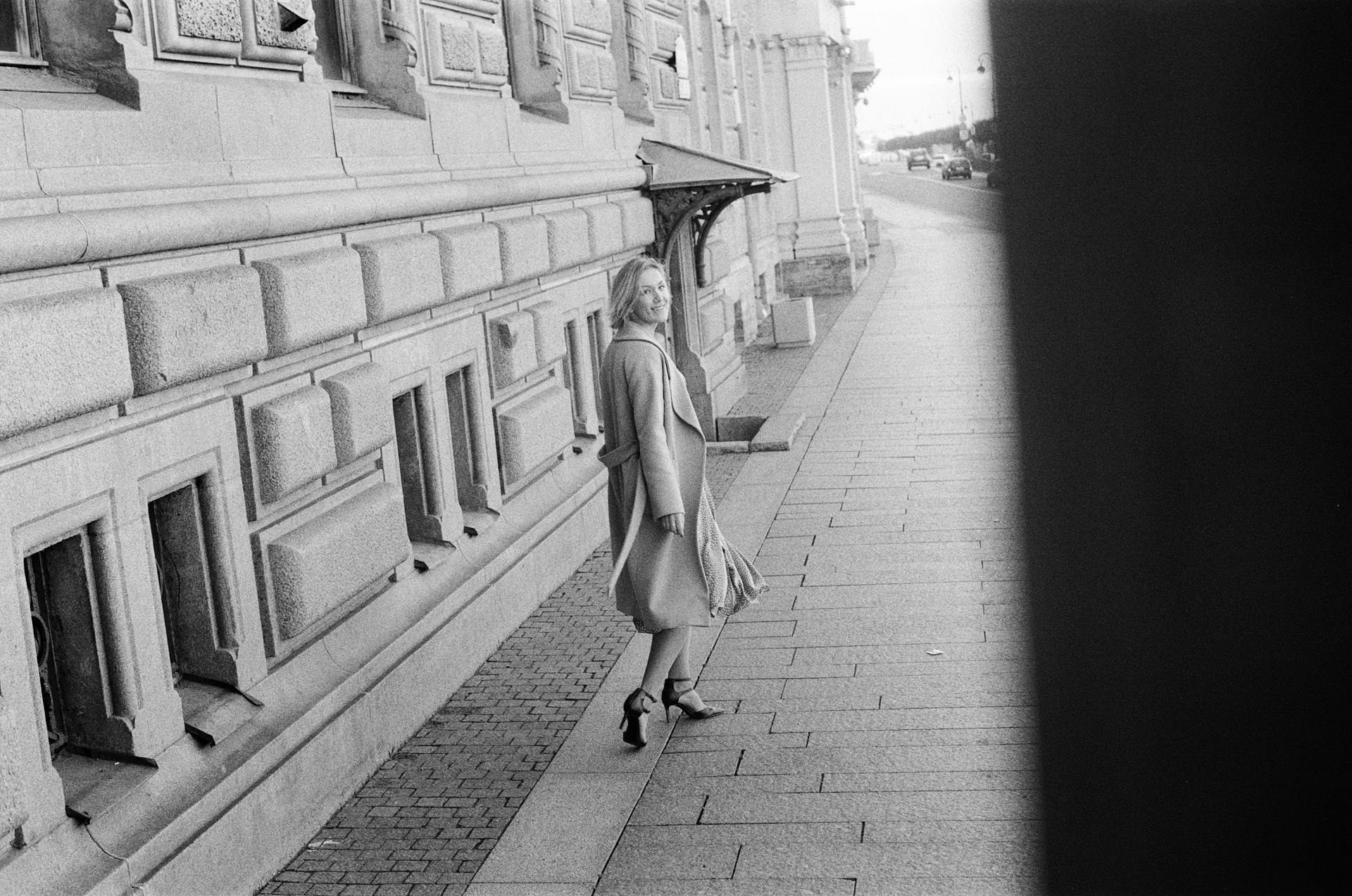 A woman walks along a St. Petersburg sidewalk, looking back. Black and white photography.