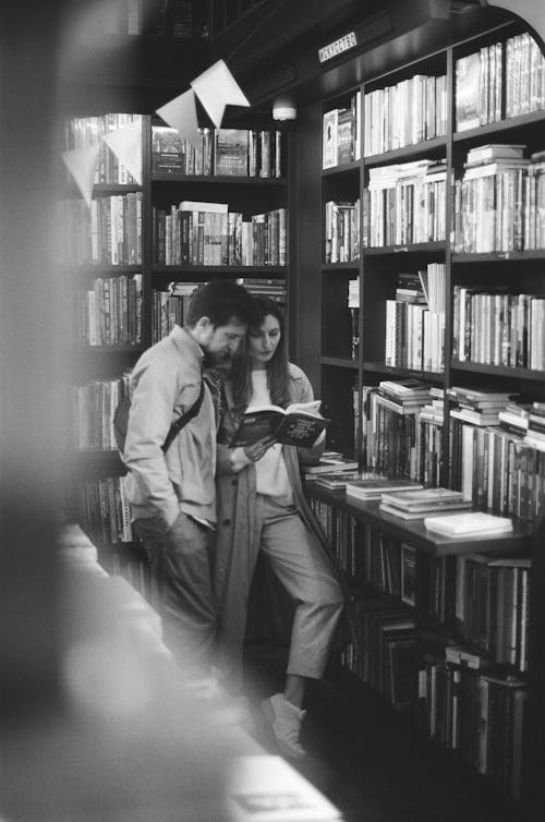Free A Couple Reading a Book in the Library Stock Photo