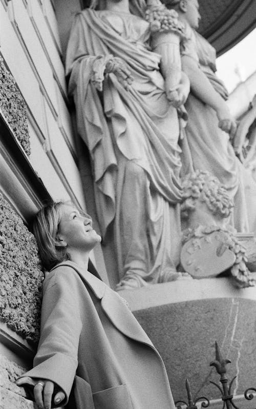 Black and White Photo of A Woman Leaning on Wall