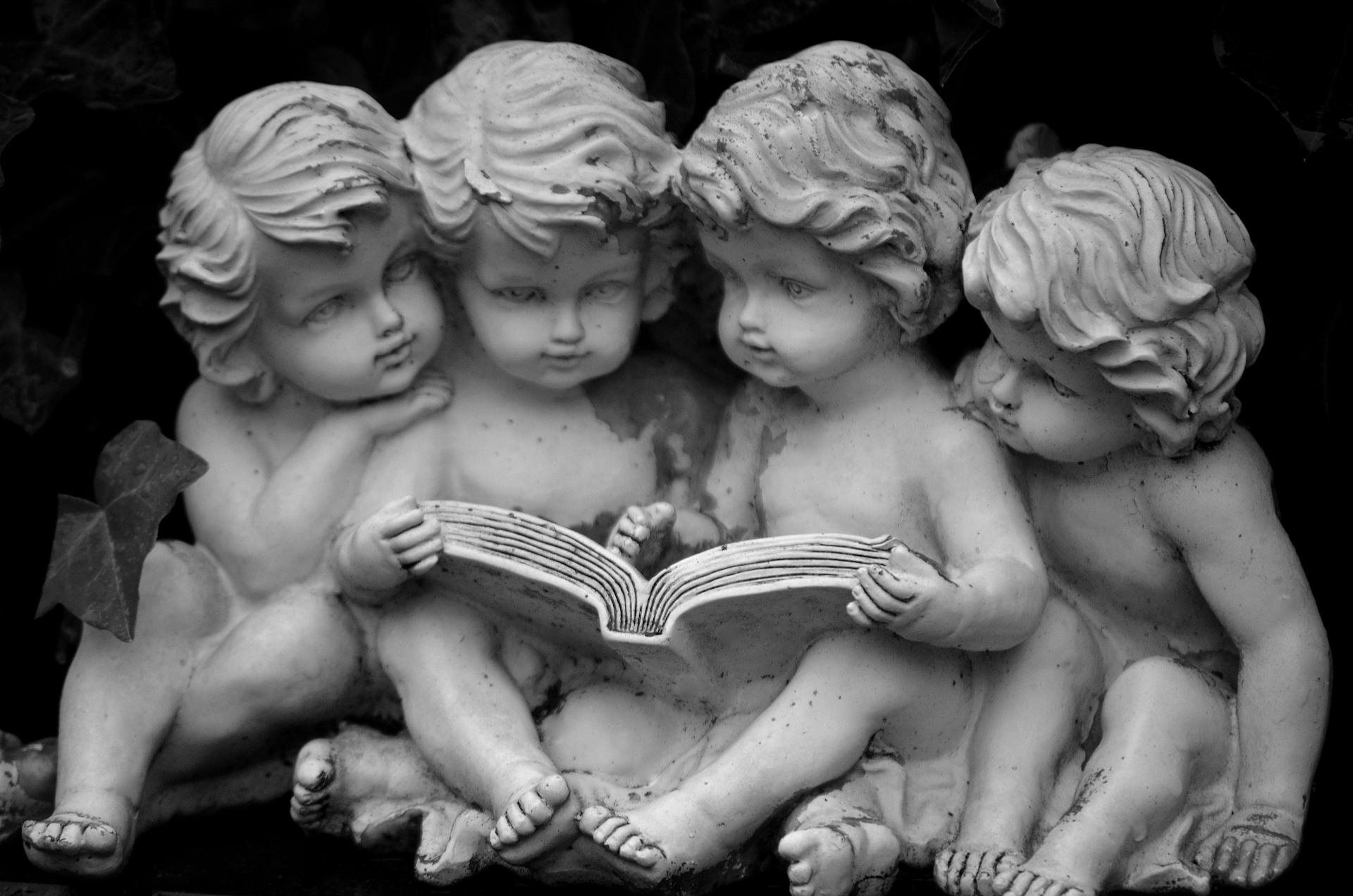 Group of cherubic statues reading together, captured in black and white.