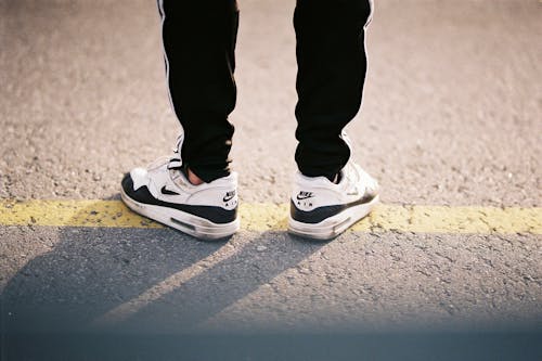 Person Standing on the Road Wearing Black Pants and Nike Air Max 90 