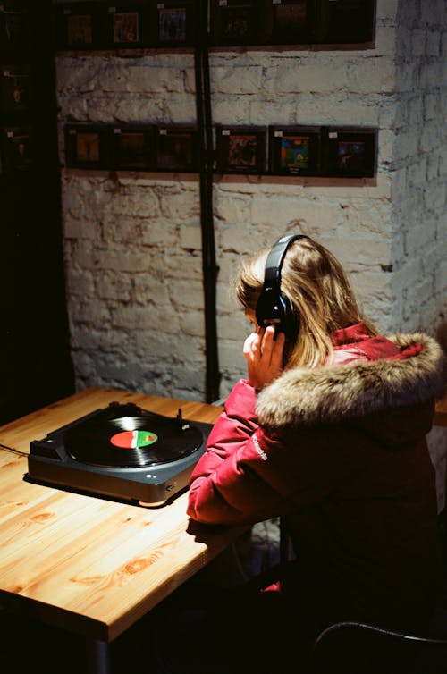 Woman in Pink Jacket listening to a Playing Vinyl Record