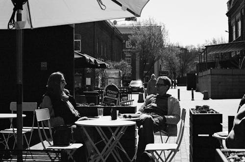 Grayscale Photo of Man and Woman Sitting on Chair in Front of Table