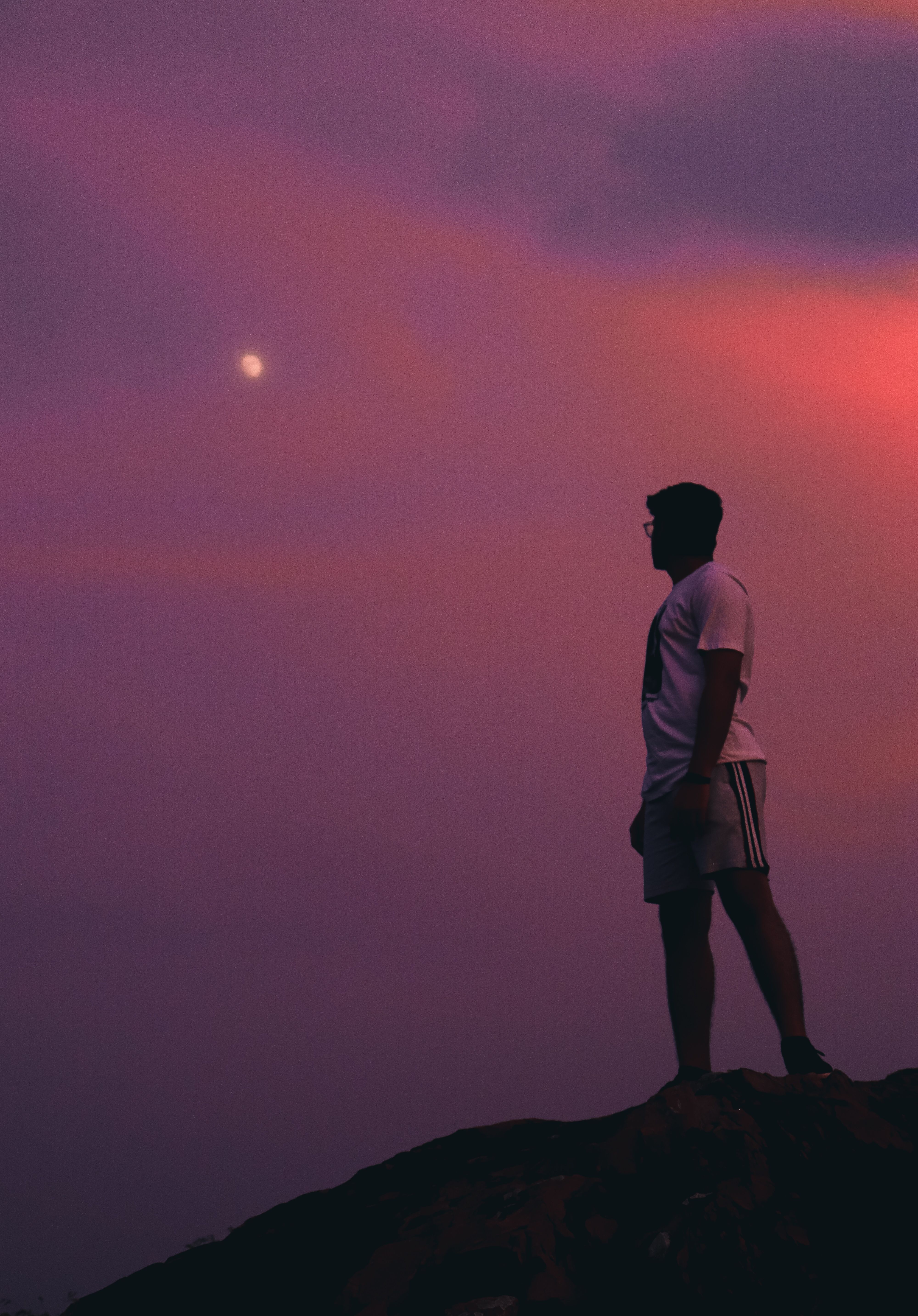 Man standing on a Rock Formation looking at the Moon · Free Stock Photo