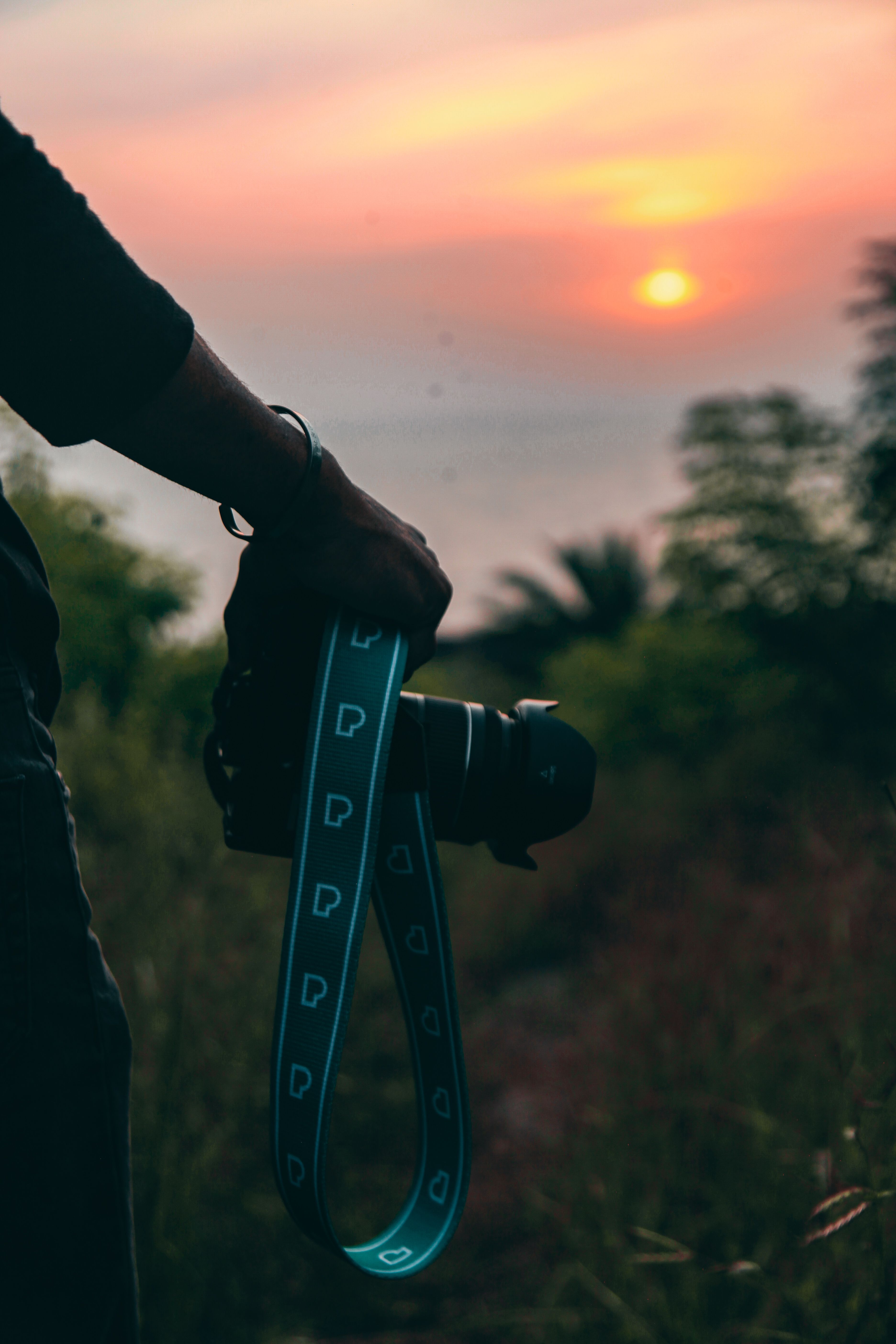 Silhouette of a photographer holding a camera during a vibrant sunset outdoors.