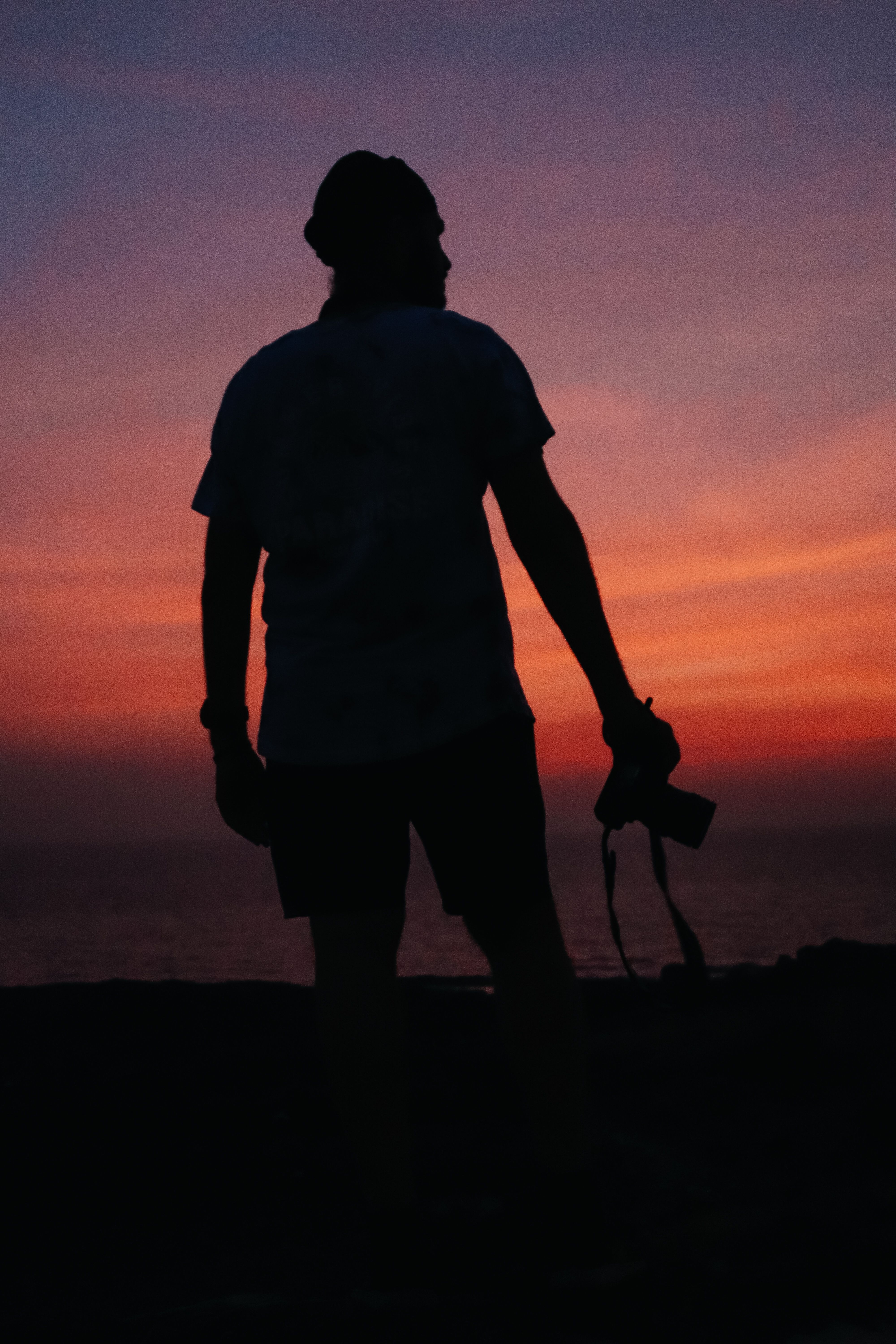 A Silhouette of a Man Holding a Camera during Twilight · Free Stock Photo