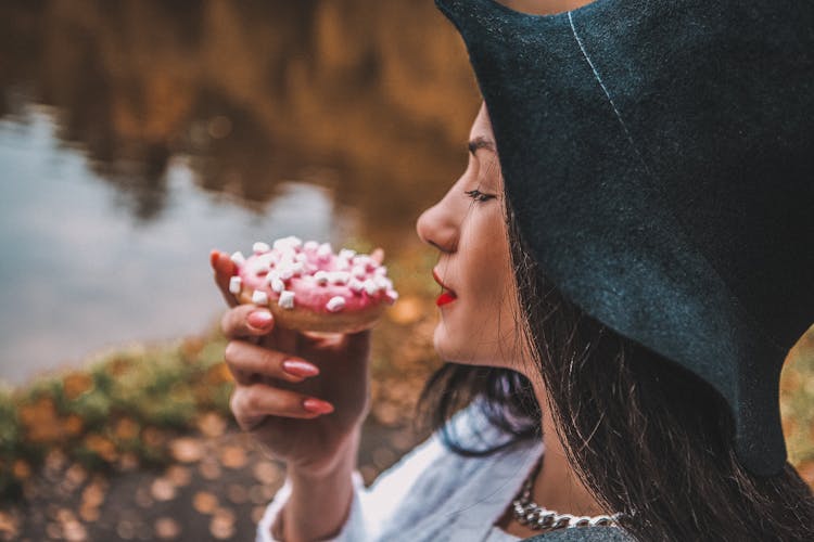 
A Woman In A Hat Eating A Donut