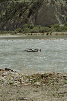 Drone captured flying over a serene river, surrounded by rocky terrain and lush greenery.
