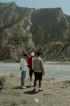 Three men enjoying a hiking adventure by a scenic mountain river in Dagestan.