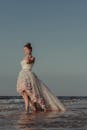 一名身穿时尚婚纱的女子赤脚站在阳光明媚的海滩上
