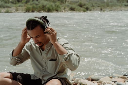 A Man Listening to Music by a River