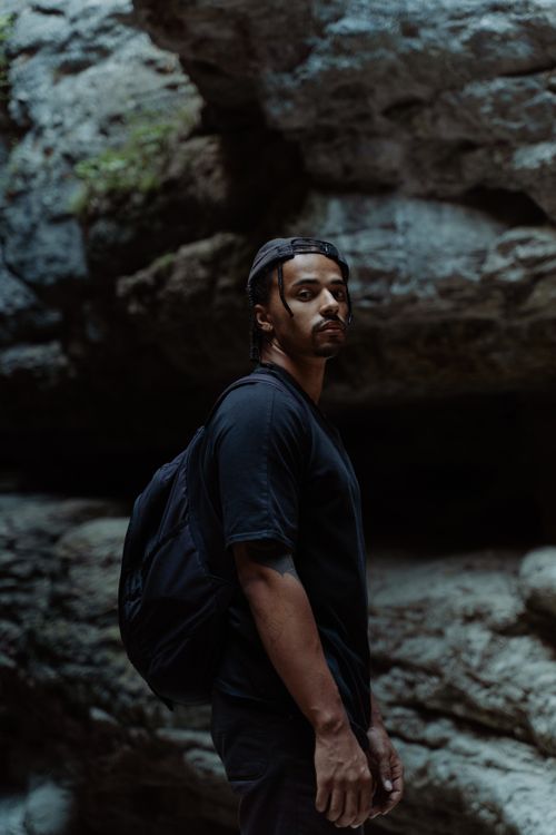 Free A confident young man with a backpack explores a rocky canyon, embracing adventure. Stock Photo