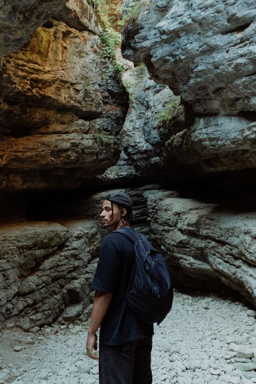 Free Man with backpack exploring a rocky canyon, embodies adventure and nature. Stock Photo