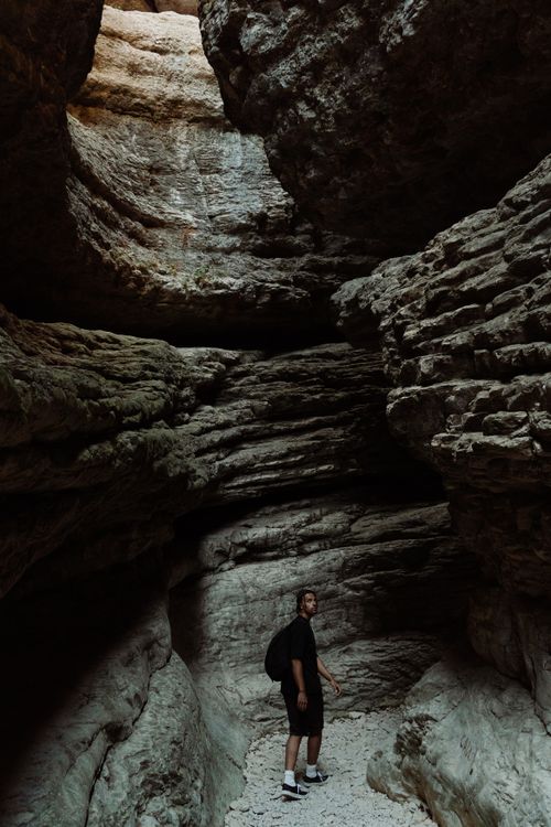 Free A man explores a vast and textured rocky cave, showcasing natural beauty and adventure. Stock Photo