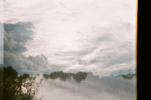 Dreamy landscape of sky reflecting in a tranquil lake at dawn, creating a peaceful and surreal scene.