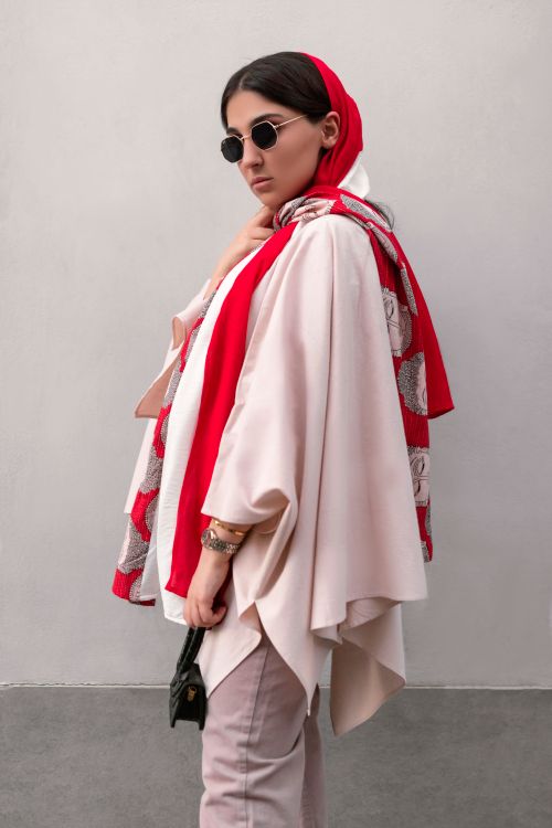 Free Stylish woman with headscarf and sunglasses posing against a gray wall in Tehran. Stock Photo