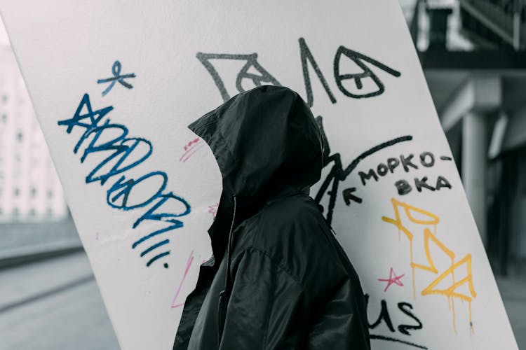 Hooded Person Against Graffiti Wall