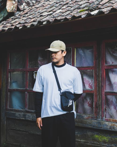 Free Man in casual attire standing in front of a rustic building in Bali, Indonesia. Stock Photo