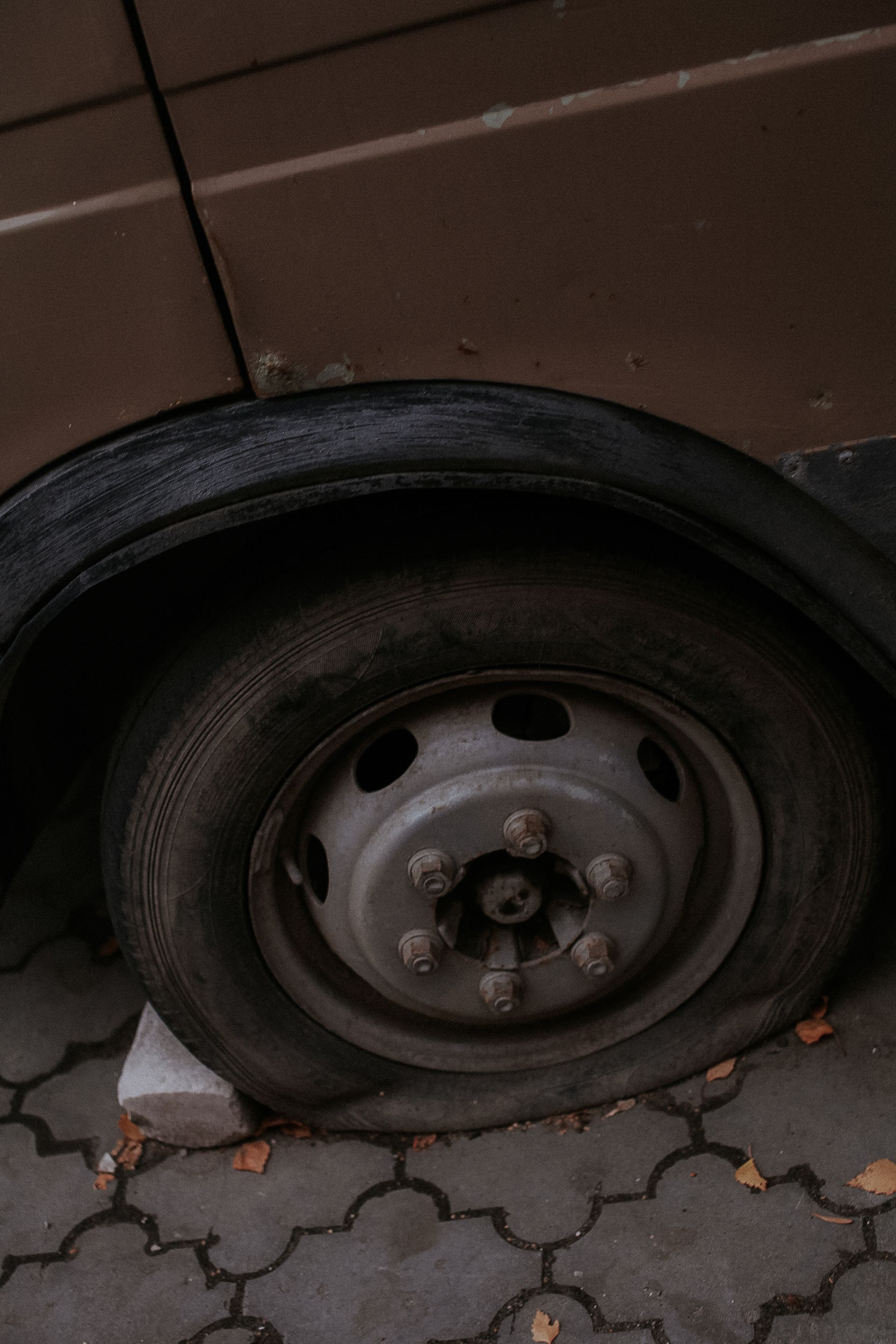 Rueda de coche pinchada apoyada sobre el bordillo