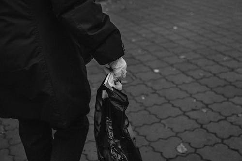 Grayscale Photo of a Person Holding a Plastic Bag