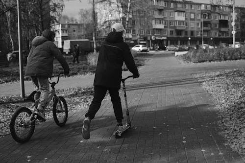 A Man in Black Jacket Riding Bicycle on Road