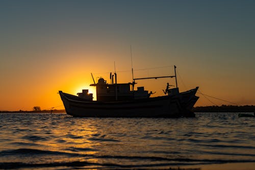 Fishing Boat on Sea during Sunset