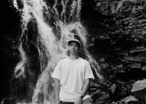 Portrait of a young man in Almaty, Kazakhstan with a waterfall backdrop. Black and white.