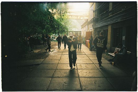 A group of people walking through an urban alley under soft lighting.